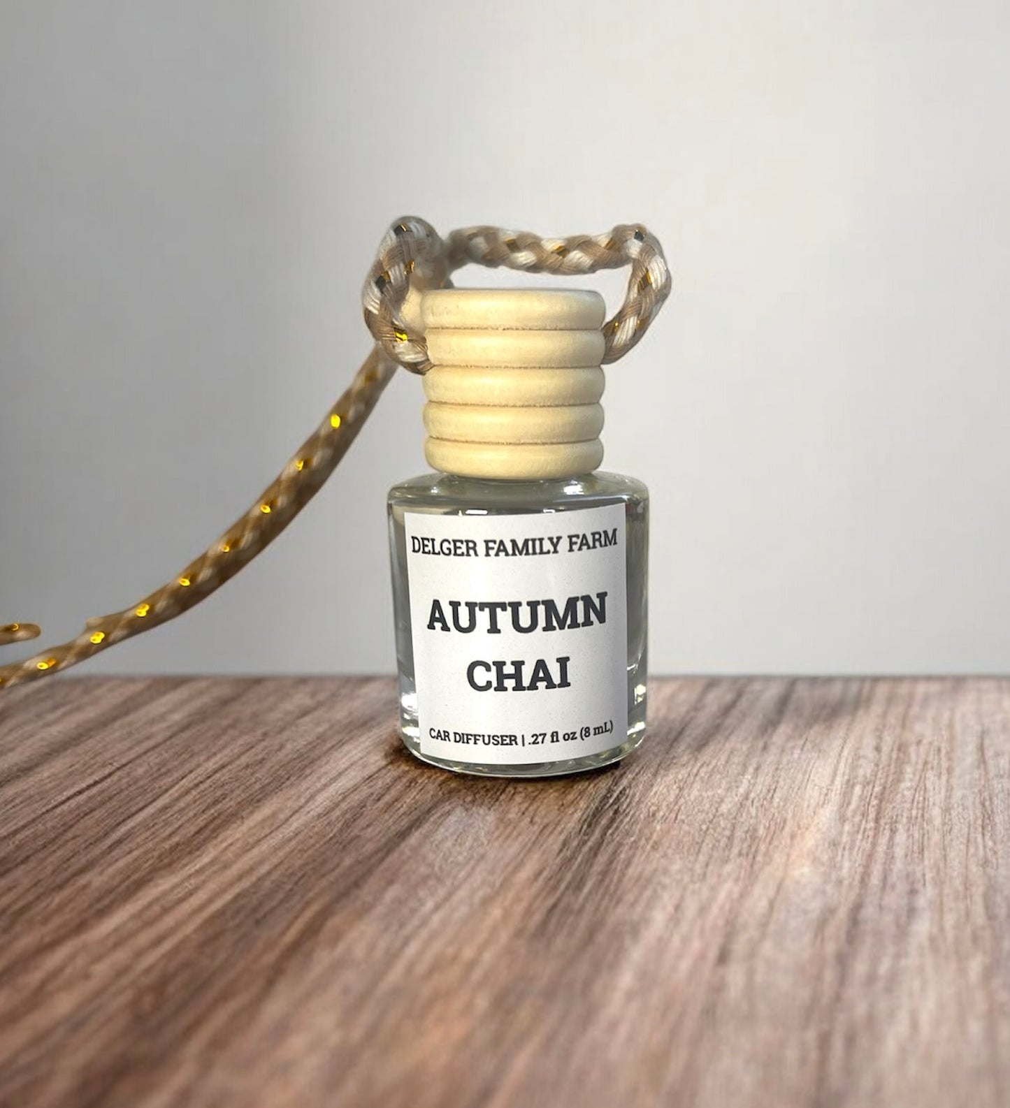 Small glass diffuser bottle labeled 'Autumn Chai' by Delger Family Farm on a wooden surface.