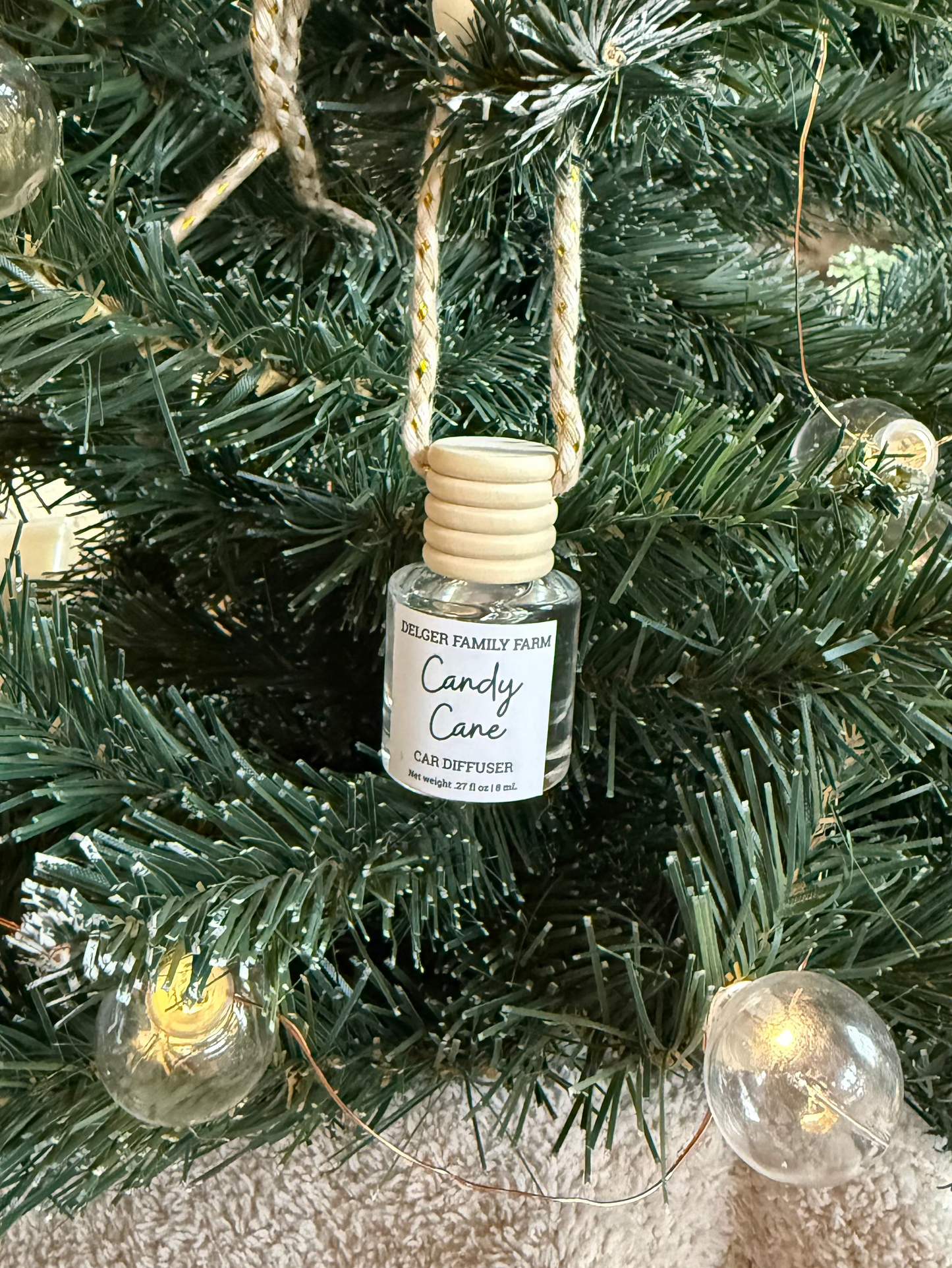Diffuser bottle labeled 'Candy Cane' hanging on a Christmas tree.