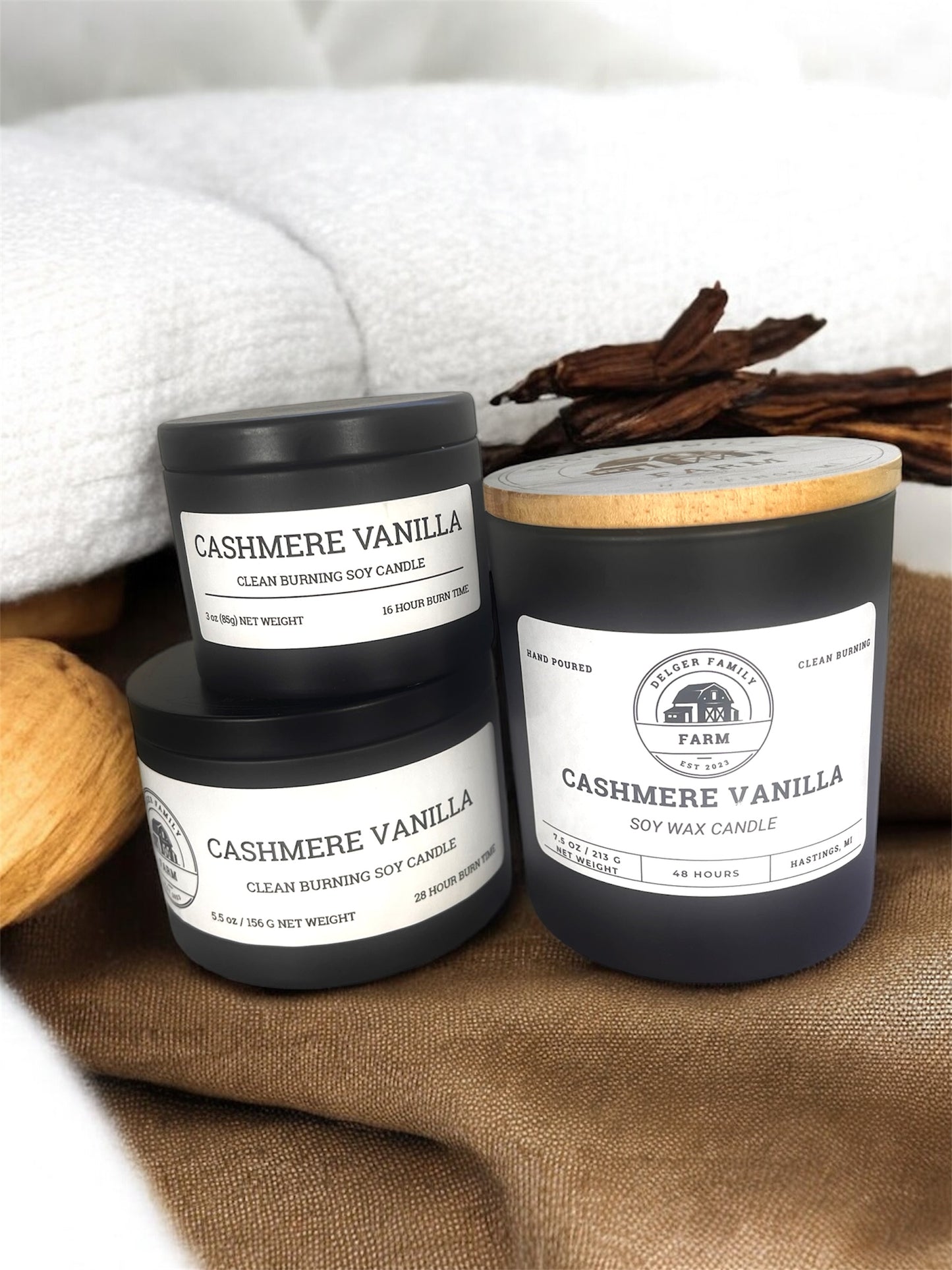 3 candles labeled cashmere vanilla stacked on top of each other resting on fabric