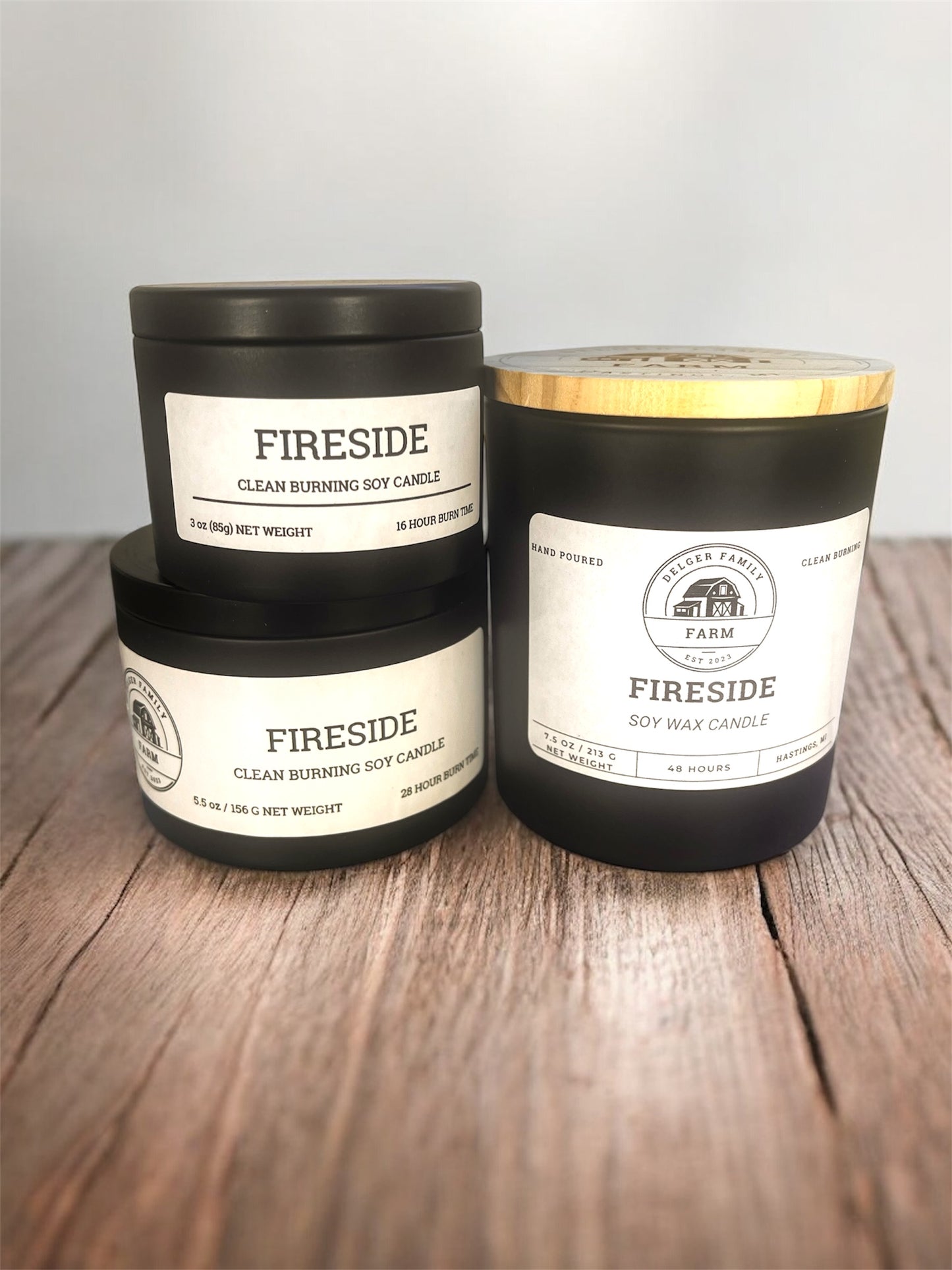 Three 'Fireside' candles on a wooden surface with a neutral background