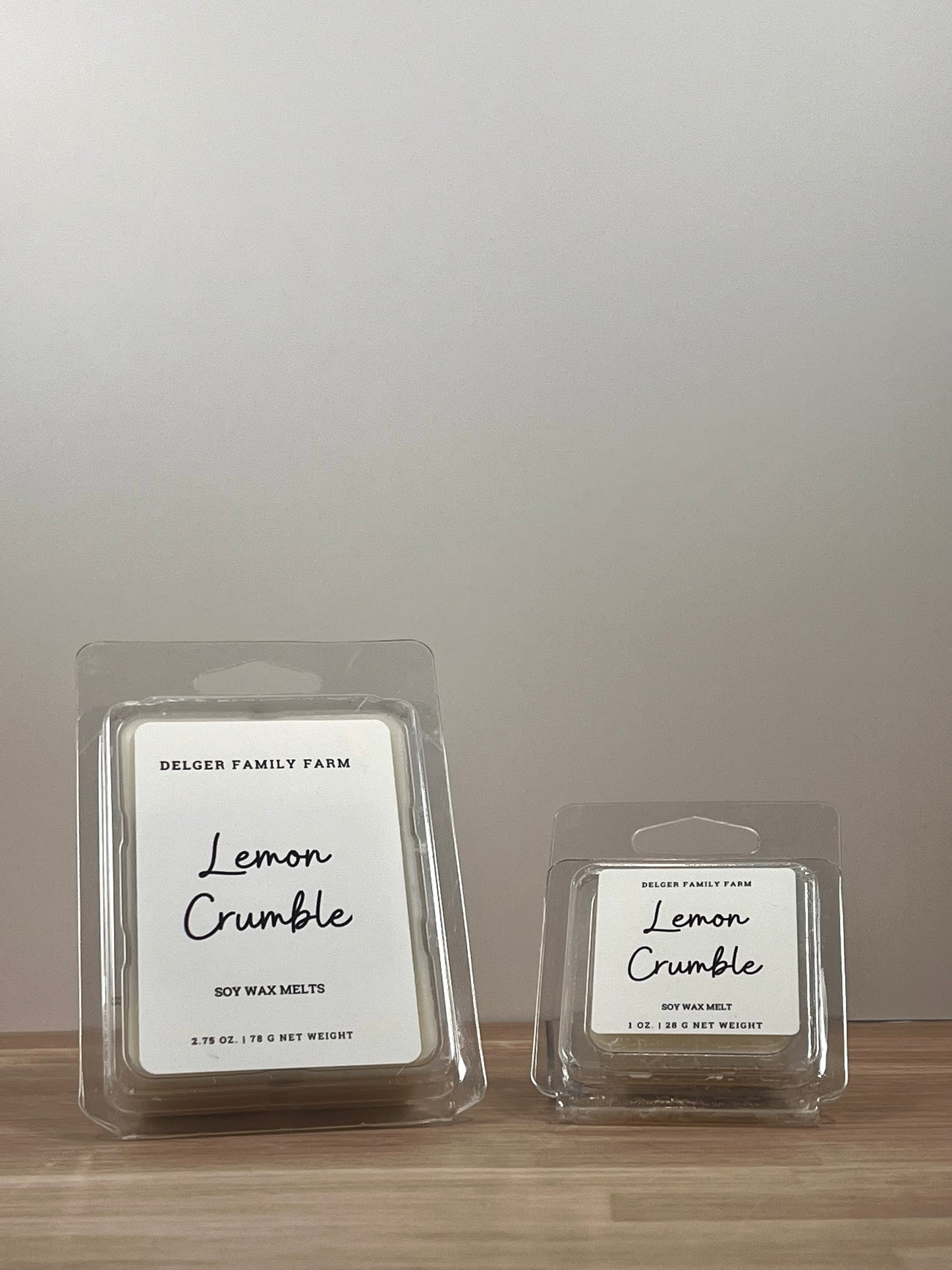 Small and large wax melt container sitting on wood.
