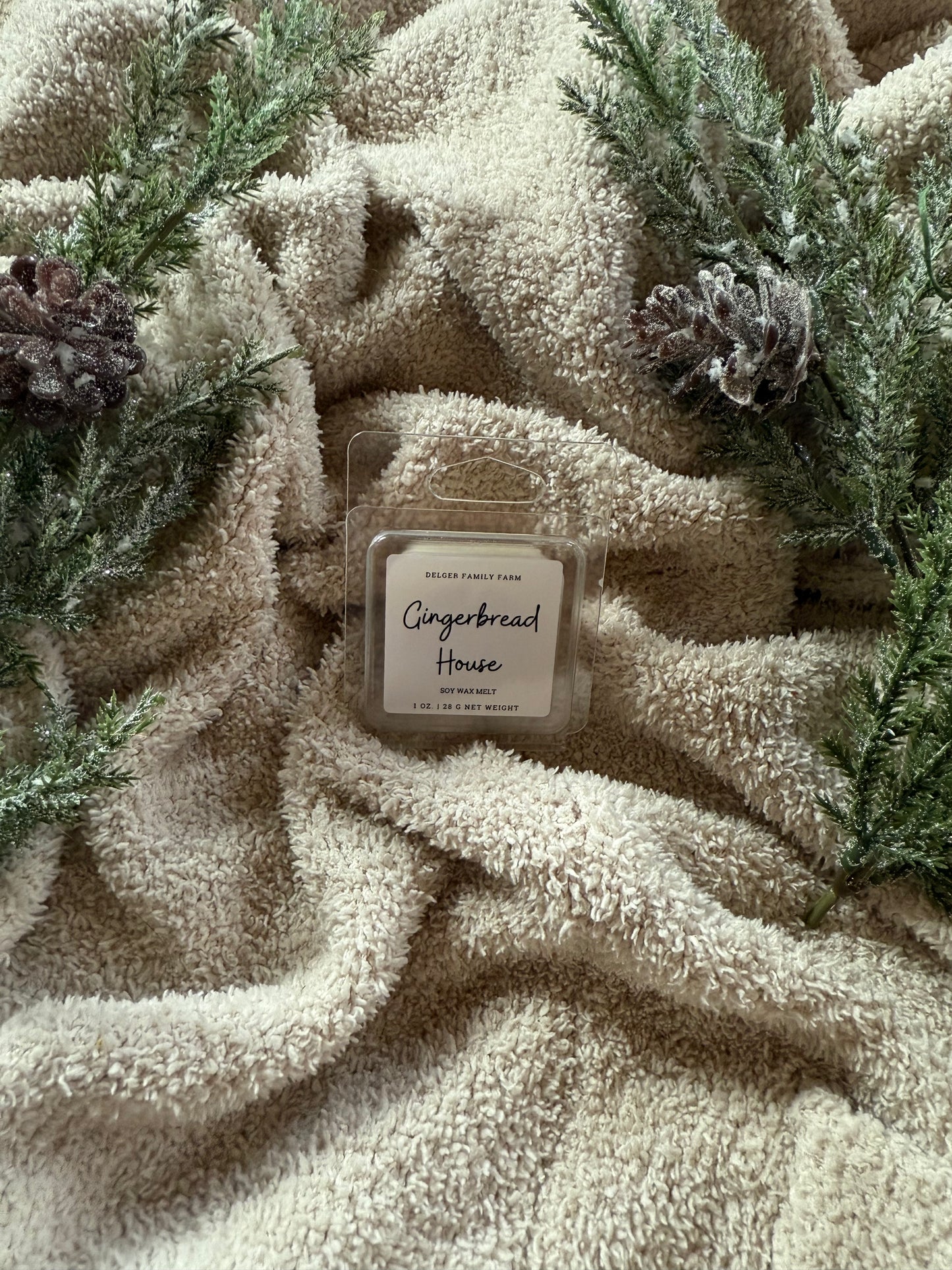 Gingerbread House wax melt on a textured beige surface with greenery