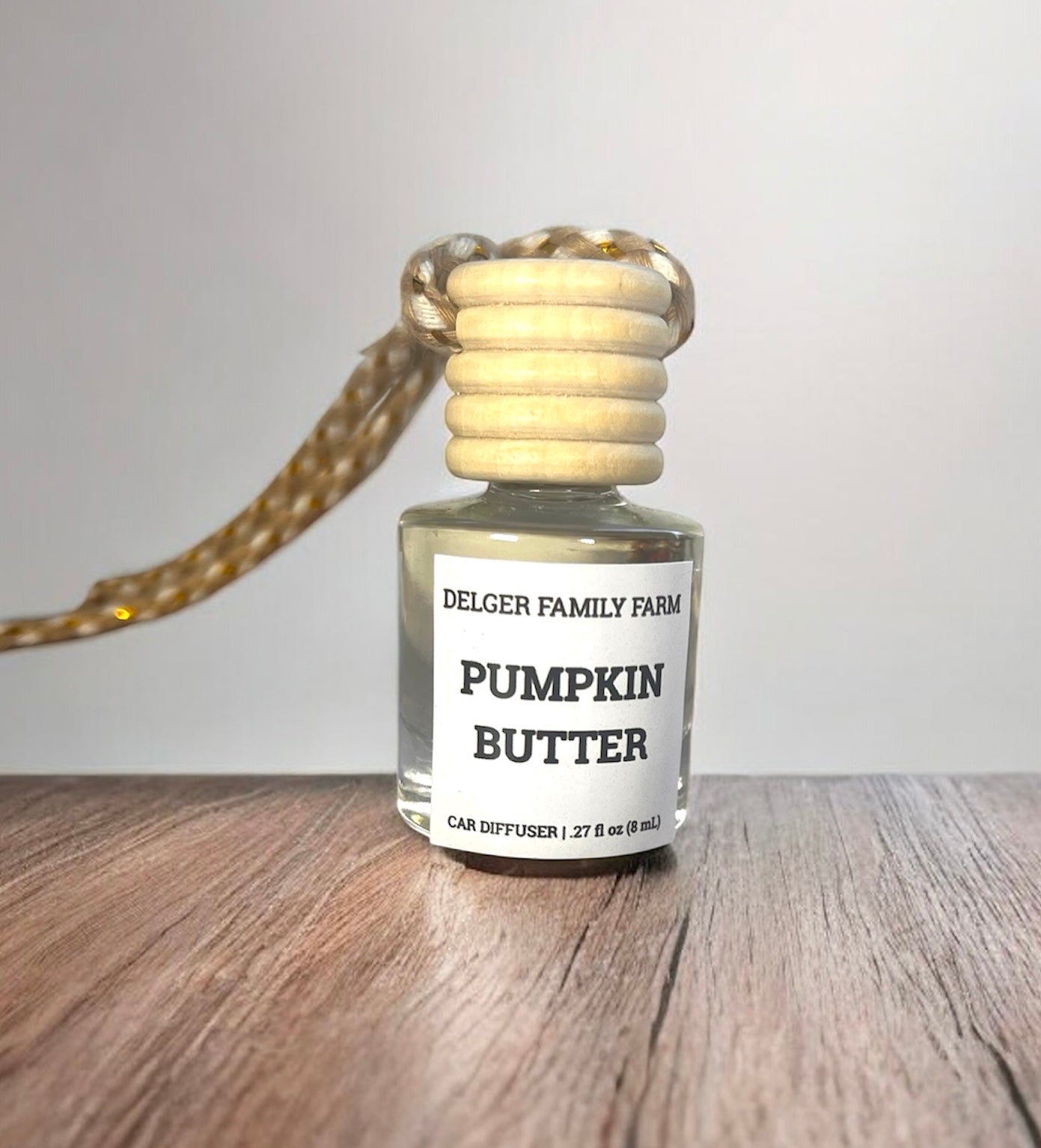Small bottle labeled 'Pumpkin Butter' by Delger Family Farm on a wooden surface with a neutral background.