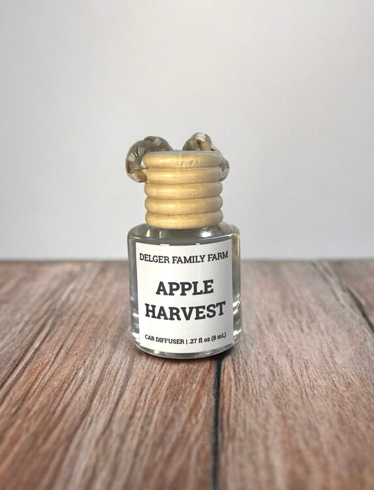 Small glass bottle labeled 'Apple Harvest' by Delger Family Farm on a wooden surface with a white background.