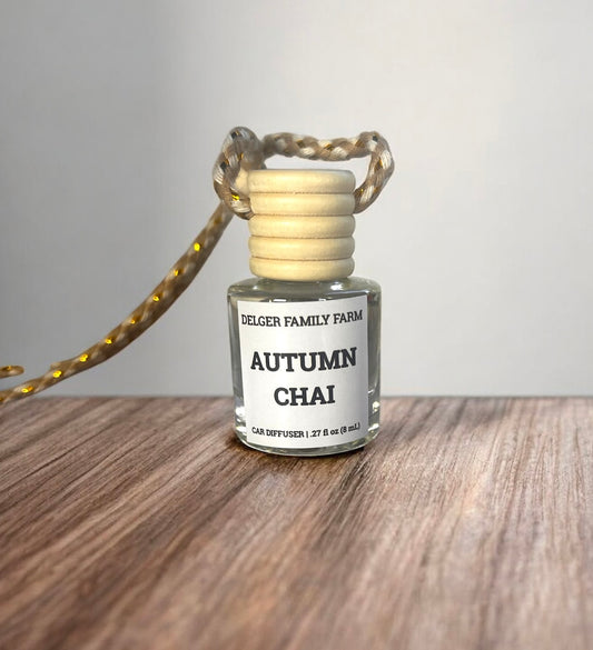 Small glass diffuser bottle labeled 'Autumn Chai' by Delger Family Farm on a wooden surface.