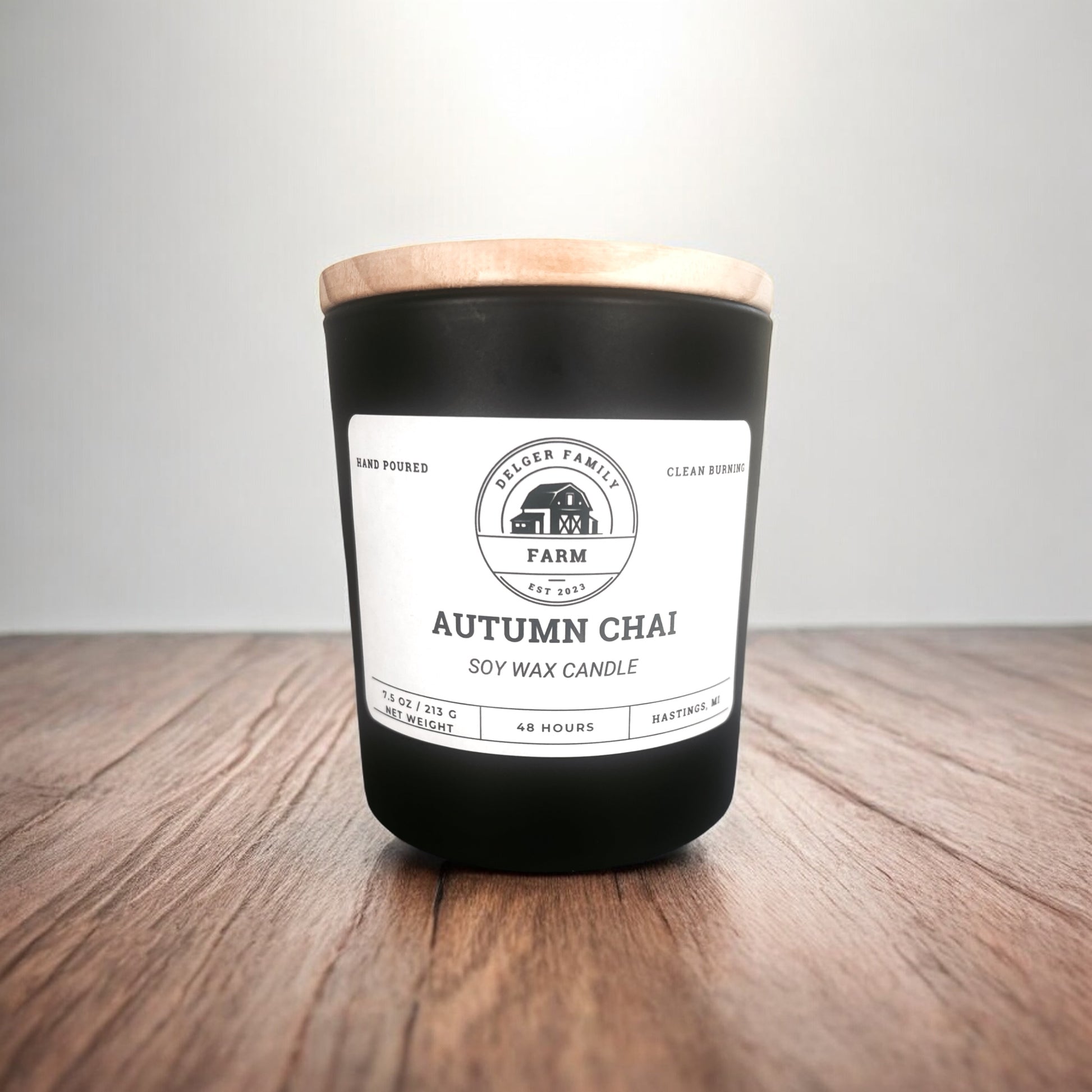 Black candle with a wooden lid on a wooden surface and gray background