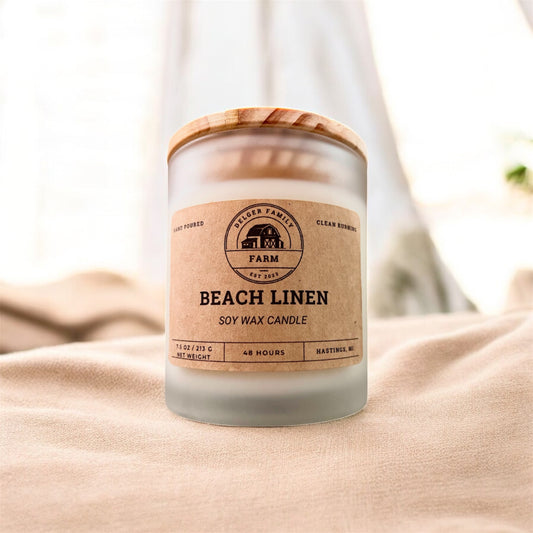 Candle labeled 'Beach Linen' on a soft fabric background