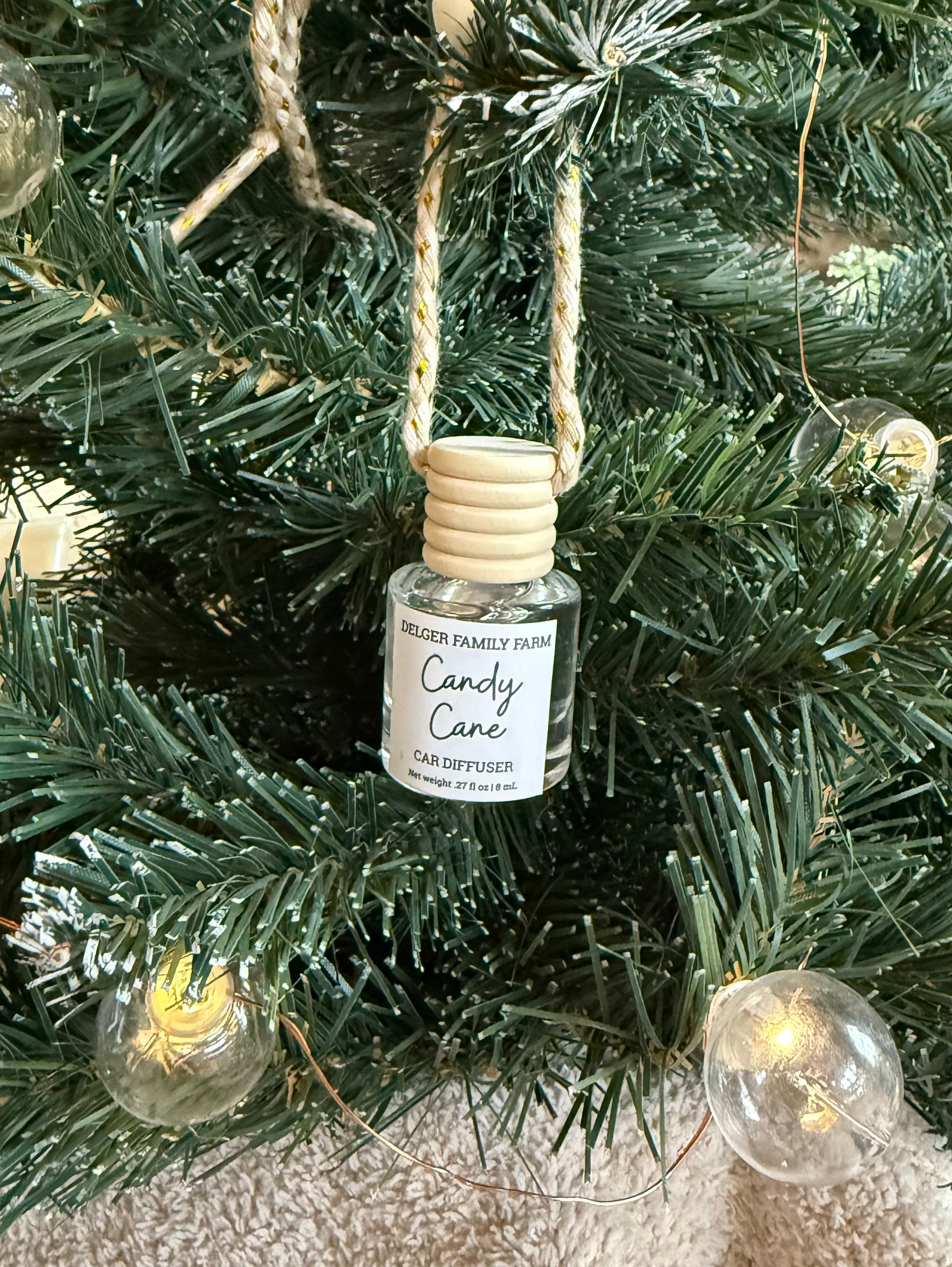 Diffuser bottle labeled 'Candy Cane' hanging on a Christmas tree.