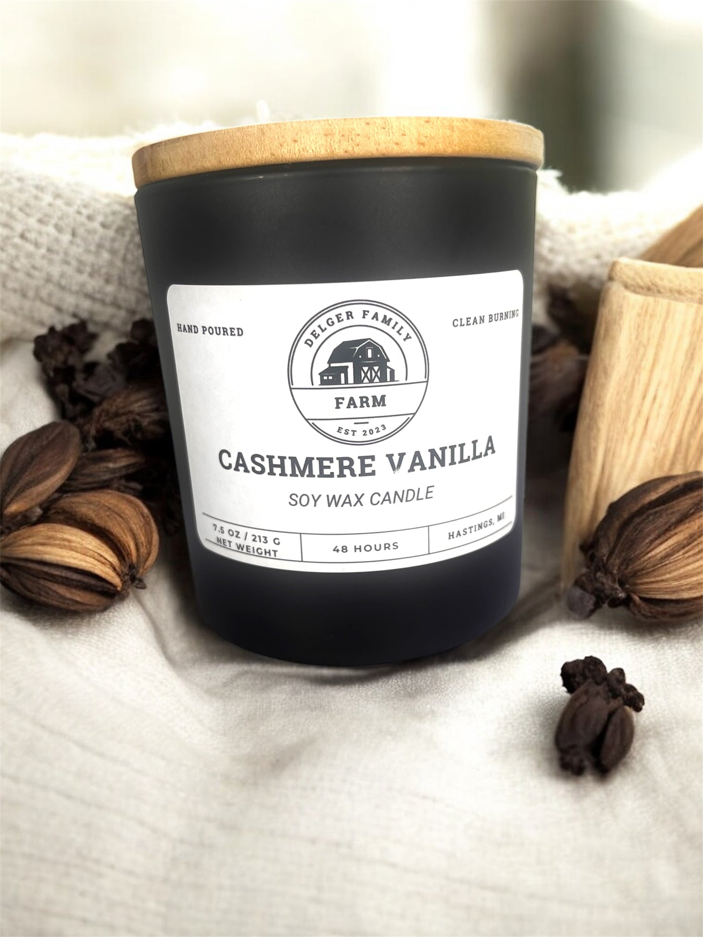 Black car jar labeled cashmere vanilla resting  on fabric 