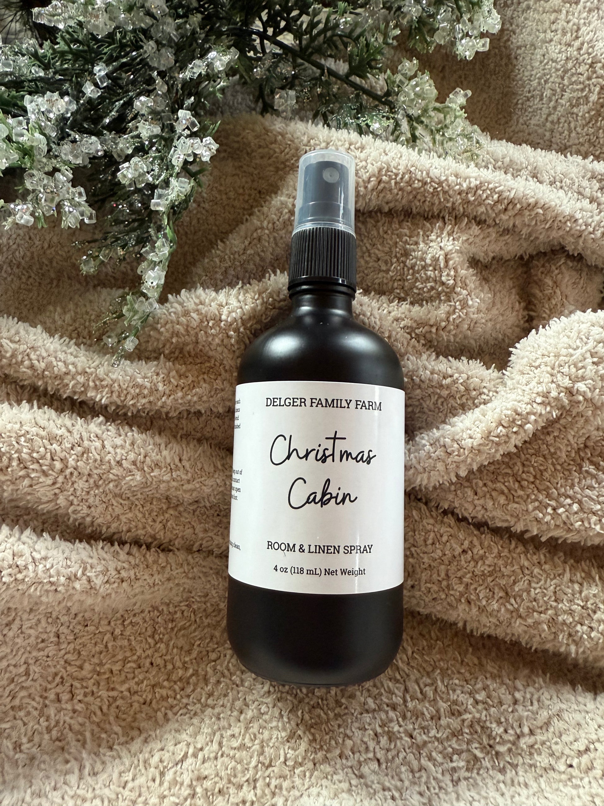 Black spray bottle labeled 'Christmas Cabin' on a textured surface with decorative elements.