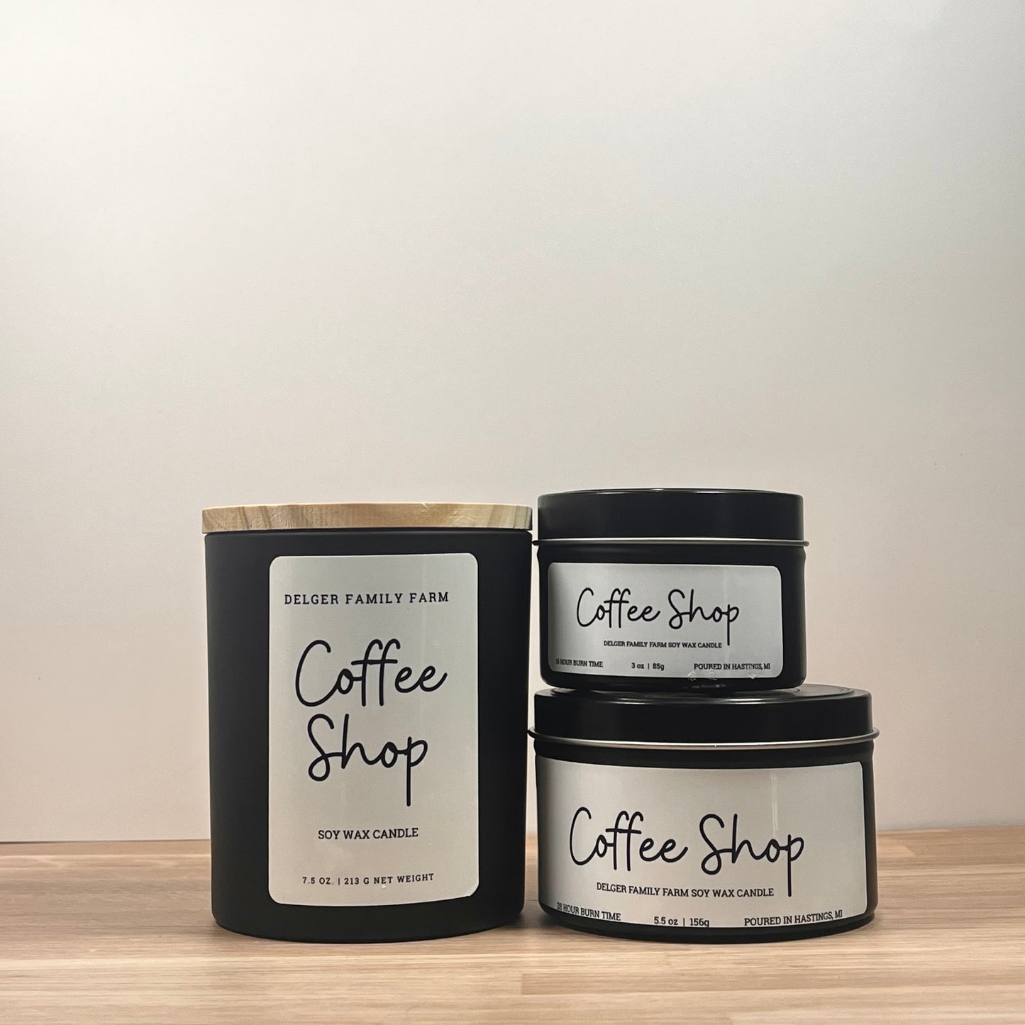 Three 'Coffee Shop' candles from Delger Family Farm on a wooden surface with a neutral background.