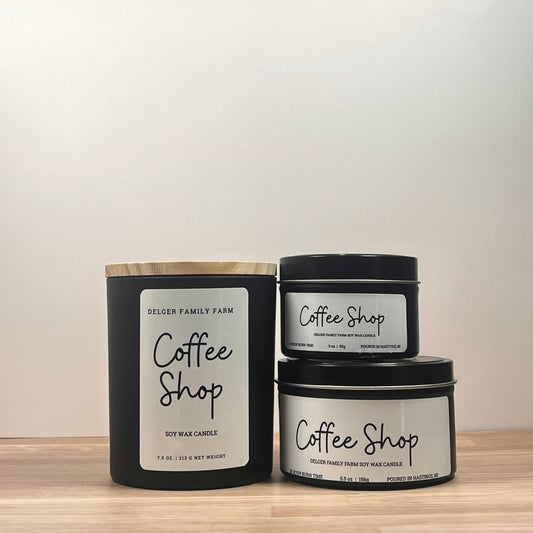 Three 'Coffee Shop' candles from Delger Family Farm on a wooden surface with a neutral background.