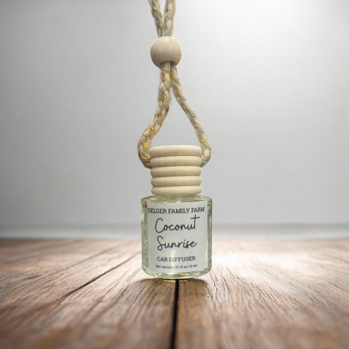 Car diffuser labeled 'Coconut Sunrise' by Delger Family Farm on a wooden surface with a white background