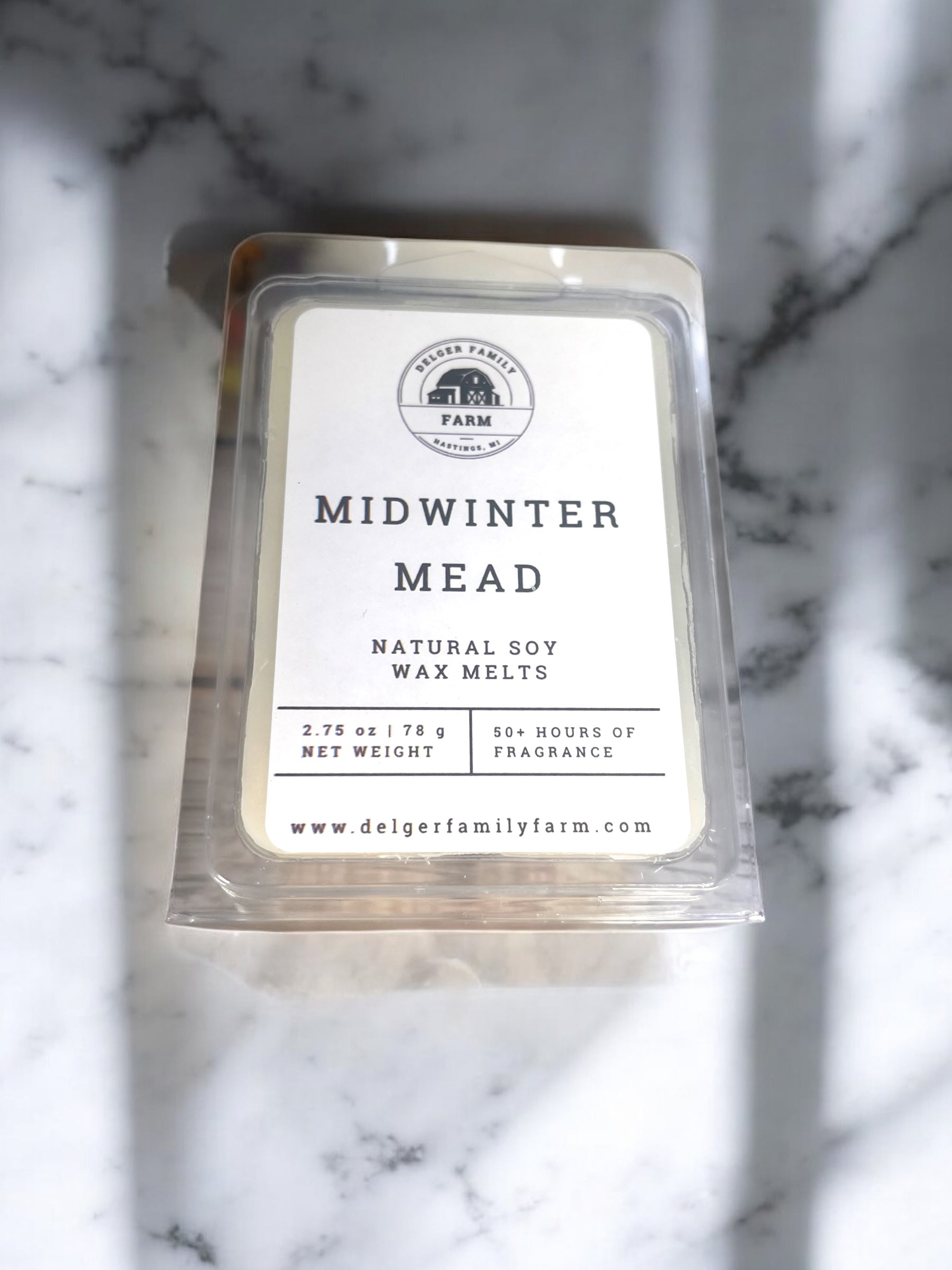 Pack of Delger Family Farm Midwinter Mead wax melts on a marble surface
