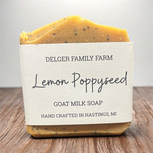 Bar of lemon poppyseed goat milk soap from Delger Family Farm on a wooden surface.