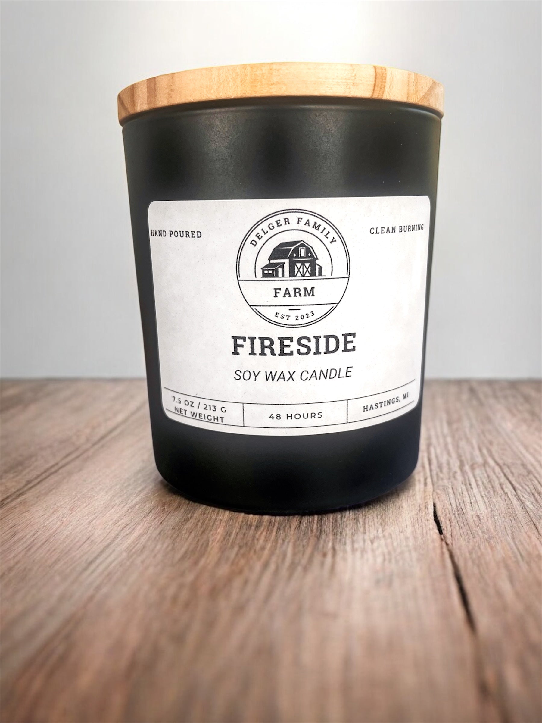 Black soy wax candle with a wooden lid on a wooden surface