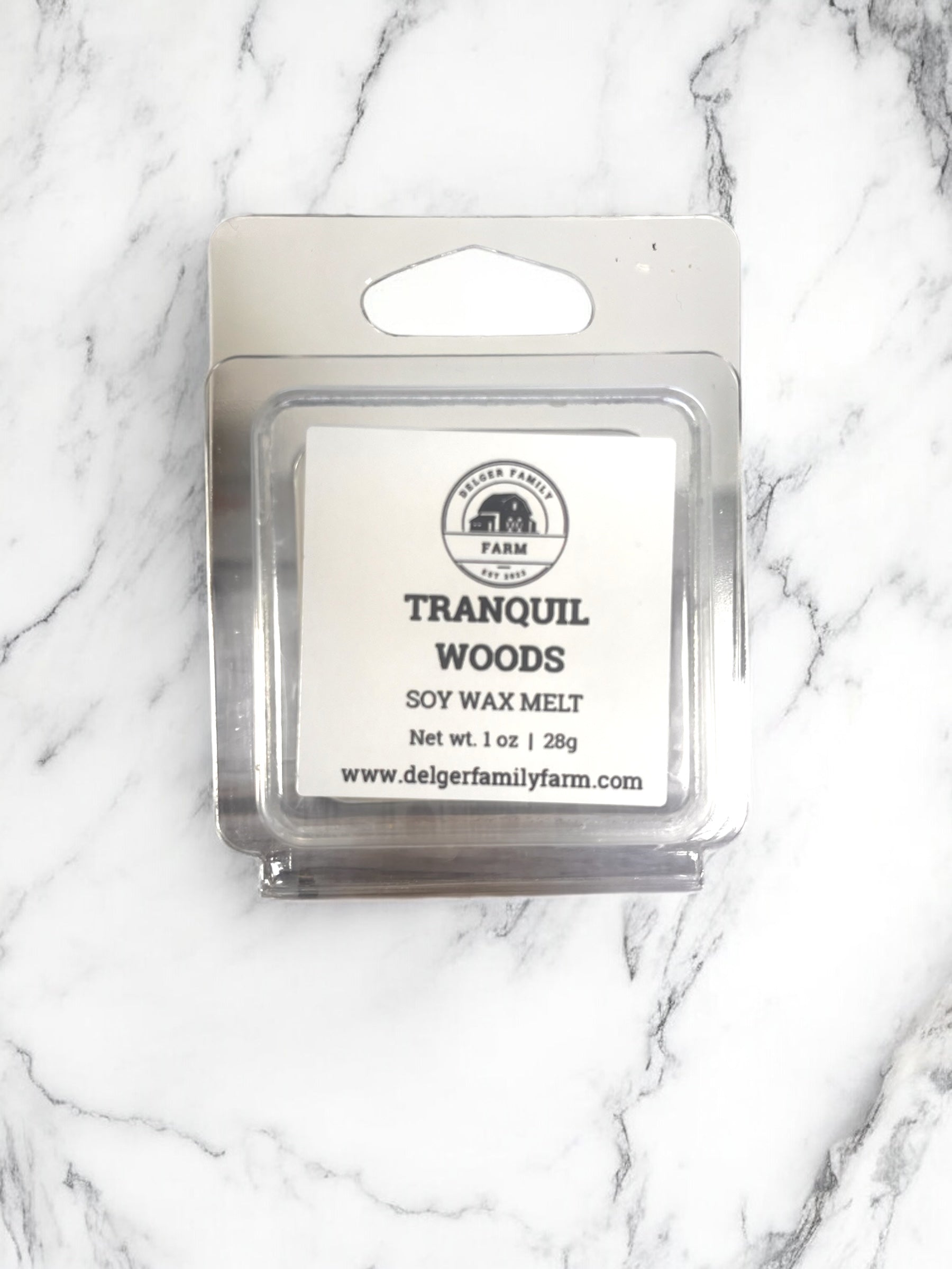 Soy wax melt package labeled 'Tranquil Woods' on a marble background
