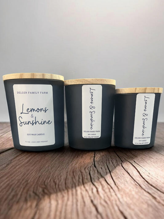 Three candles labeled 'Lemons & Sunshine' on a wooden surface with a gray background