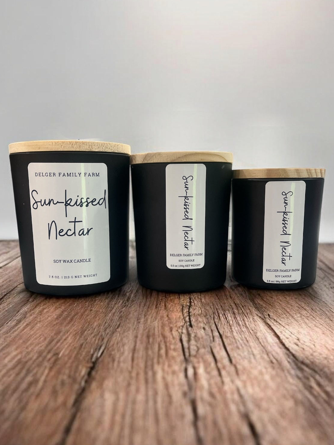 Three black candles with wooden lids on a wooden surface against a gray background