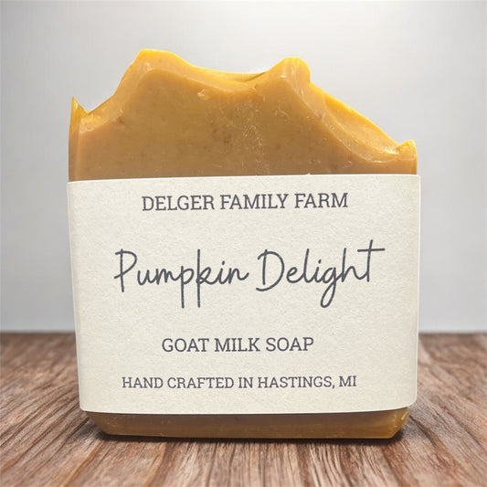 Bar of soap labeled 'Pumpkin Delight' from Delger Family Farm on a wooden surface.