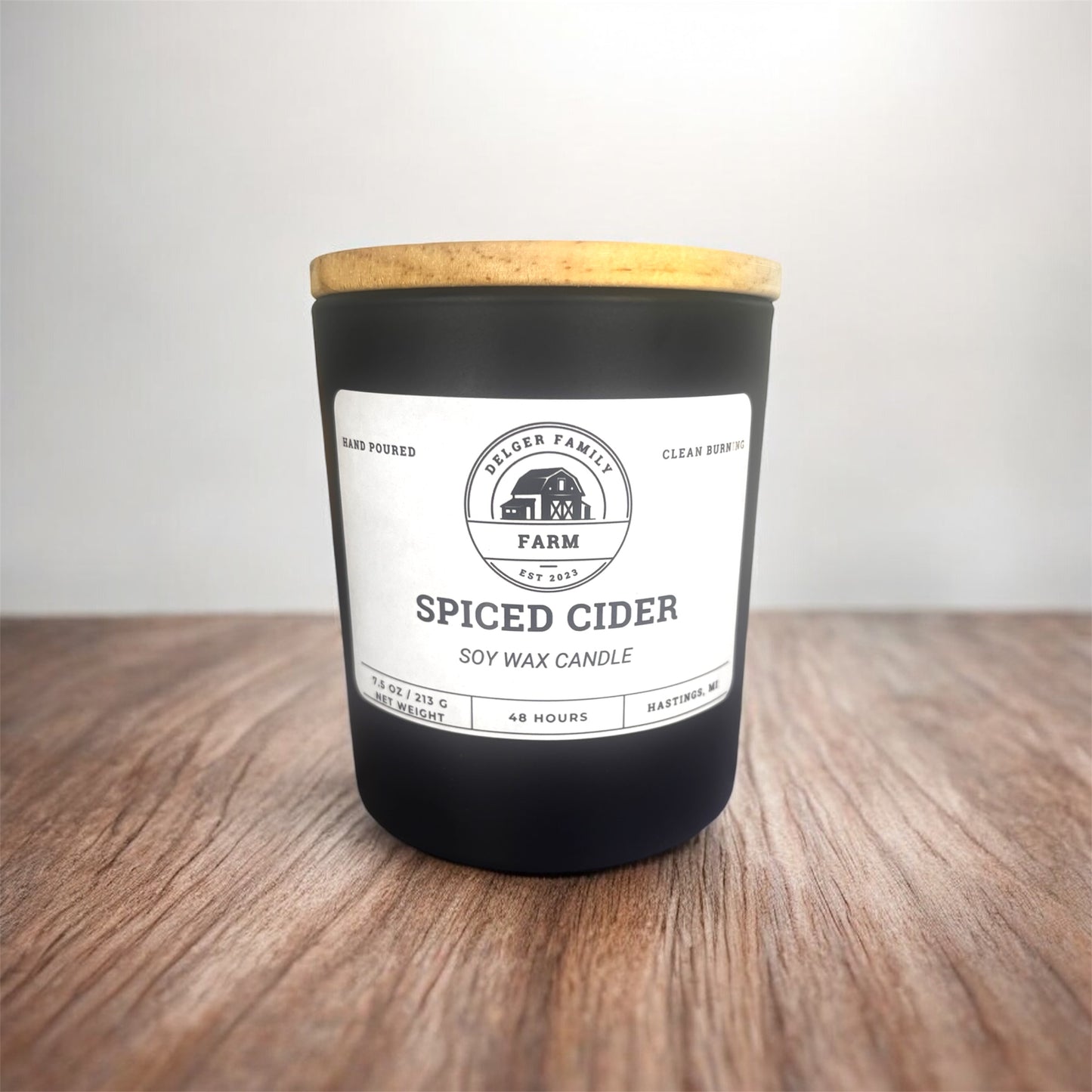 Spiced Cider candle with a wooden lid on a wooden surface