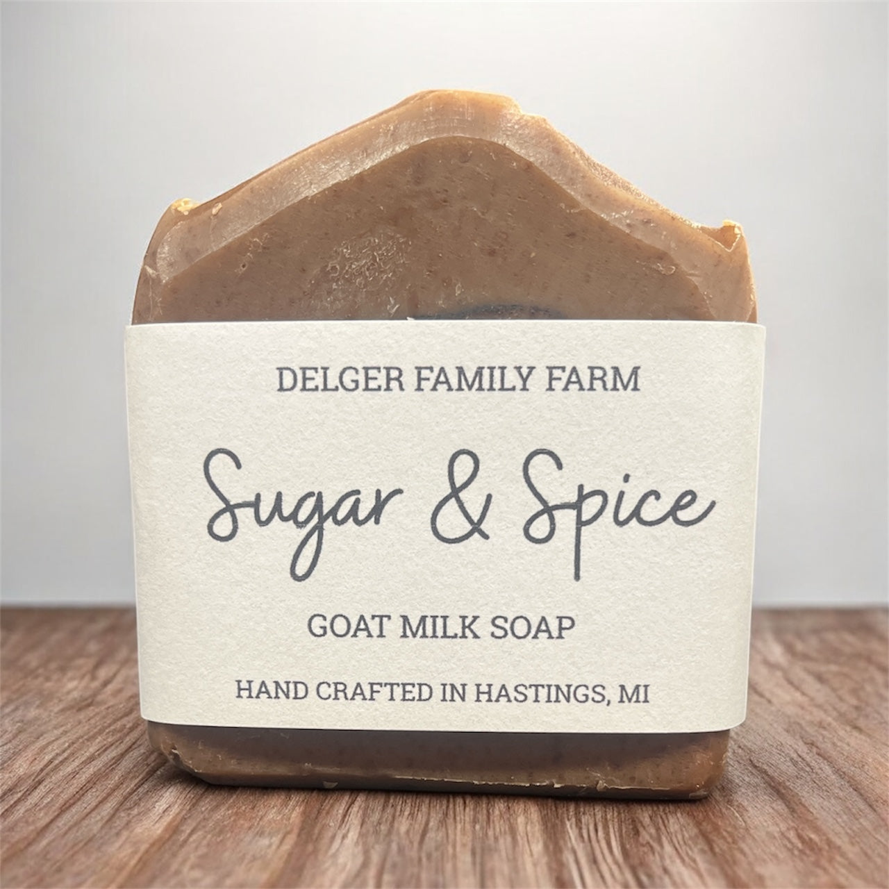 Bar of soap with 'Delger Family Farm Sugar & Spice Goat Milk Soap' label on a wooden surface.