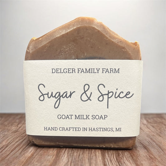 Bar of soap with 'Delger Family Farm Sugar & Spice Goat Milk Soap' label on a wooden surface.