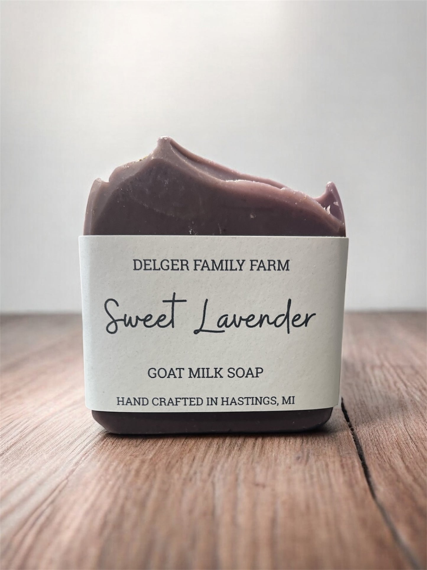 Bar of soap labeled 'Sweet Lavender' from Delger Family Farm on a wooden surface.