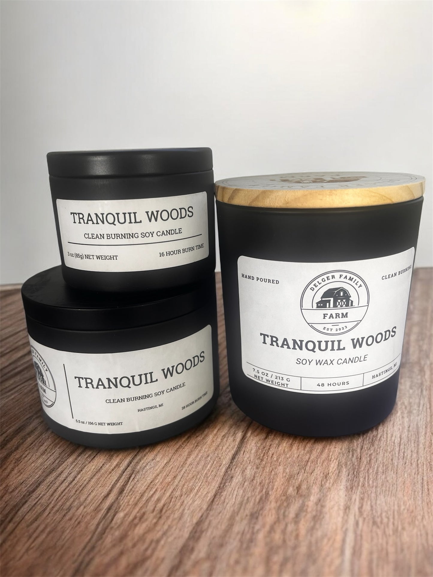 Three Tranquil Woods candles on a wooden surface with a white background