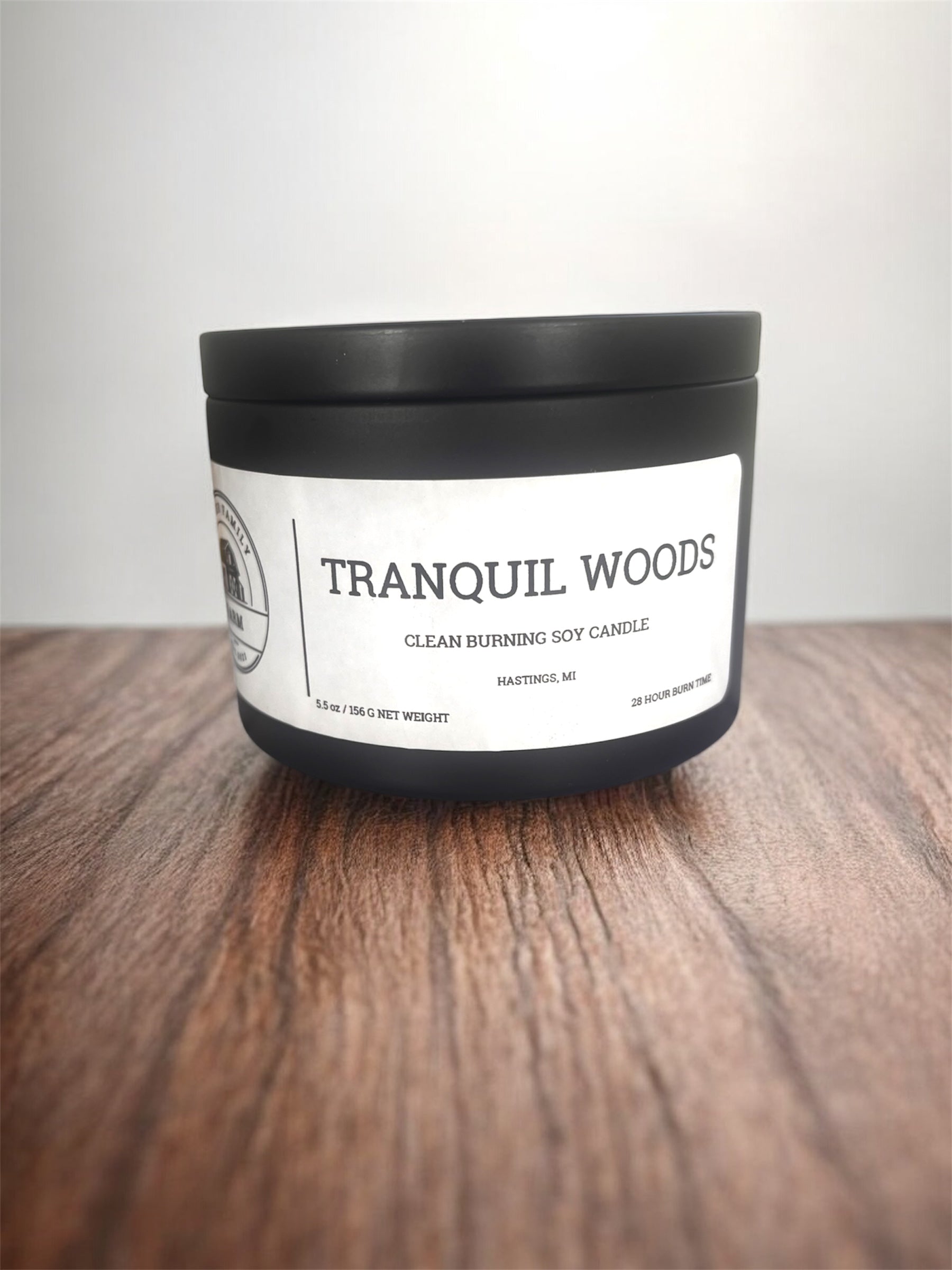 Candle labeled 'Tranquil Woods' on a wooden surface with a white background