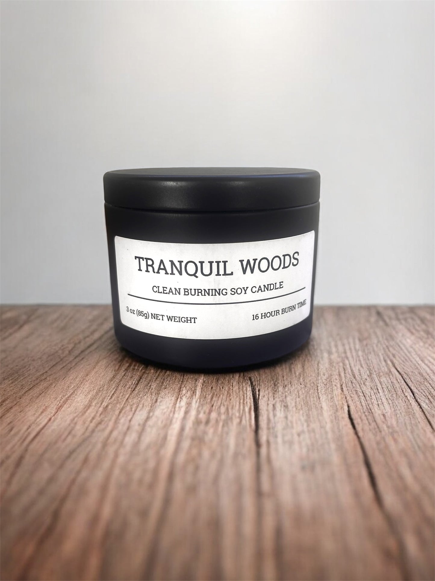 Candle labeled 'Tranquil Woods' on a wooden surface with a white background