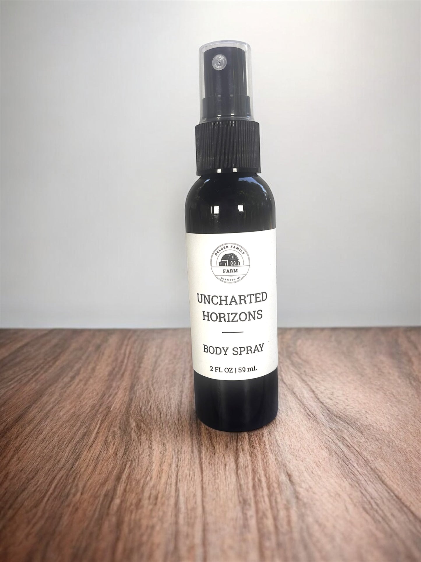 Black body spray bottle with white label on wooden surface with white background