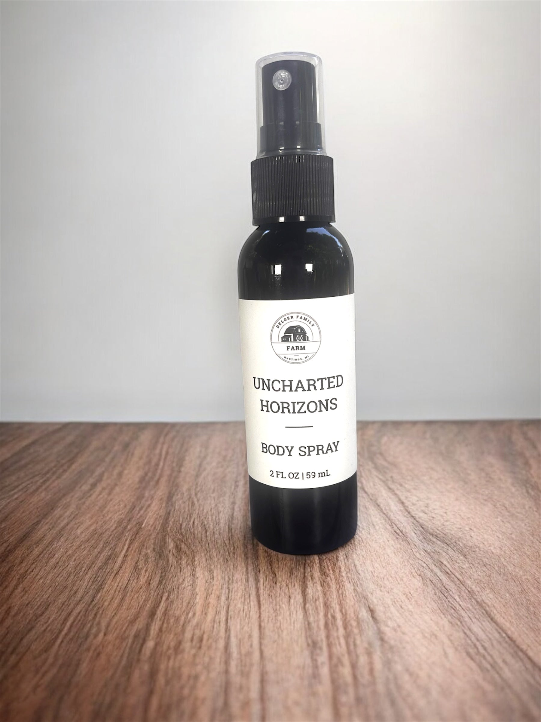 Black body spray bottle with white label on wooden surface with white background