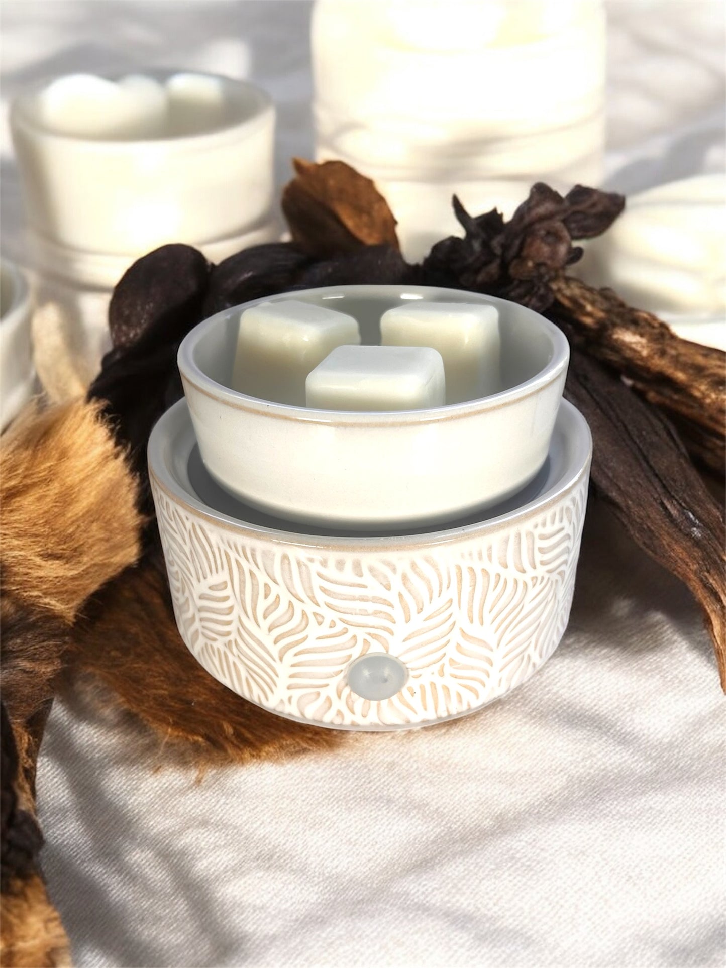 White ceramic diffuser with decorative elements on a soft surface